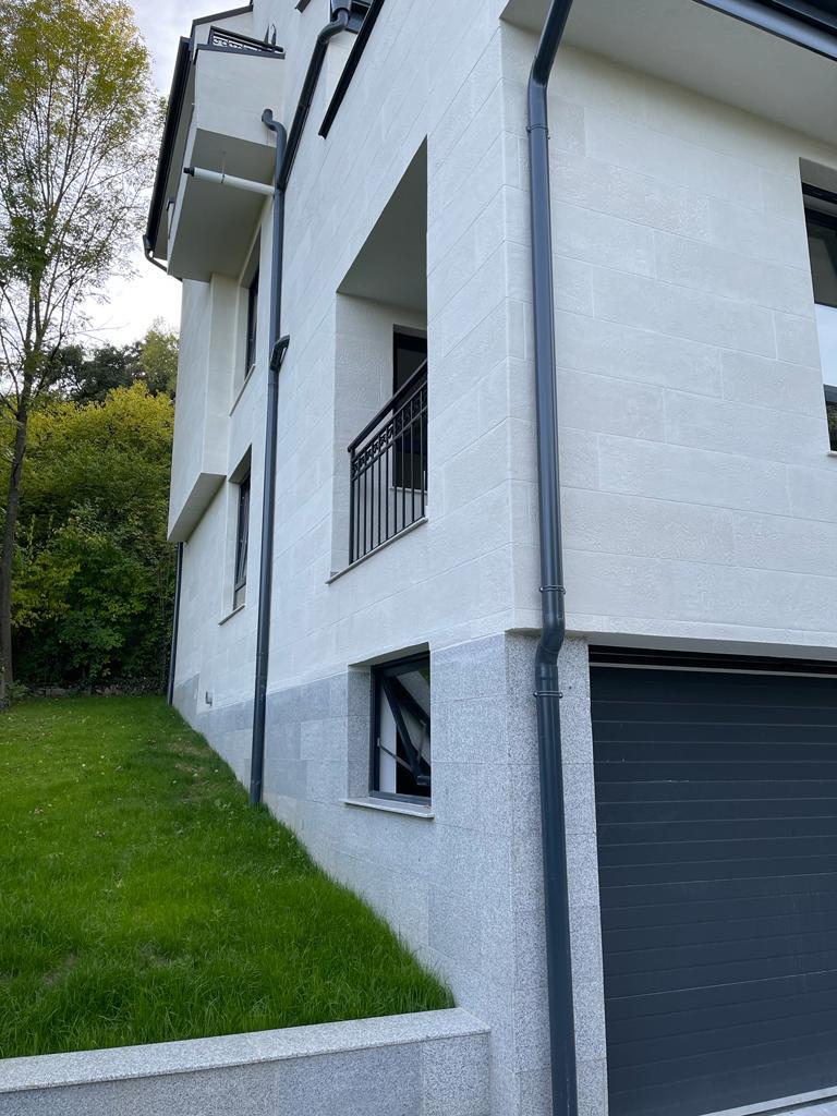 Junction of white flexible stone and the granite plinth above the garage door