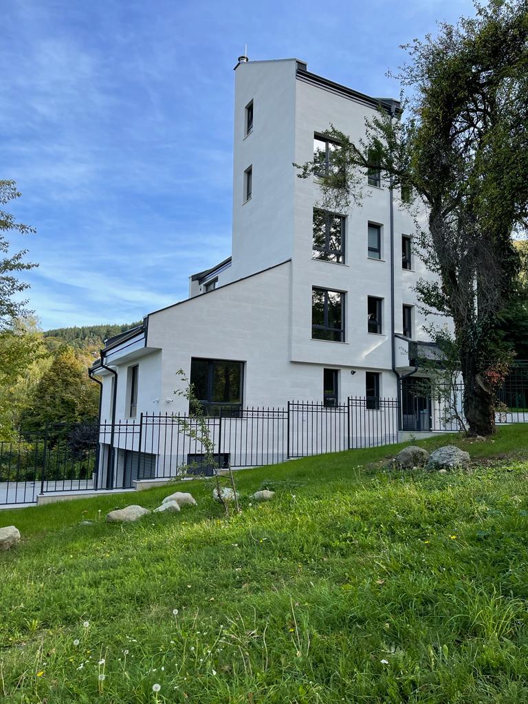 White house on a slope with a tower volume clad in Butcher White flexible stone