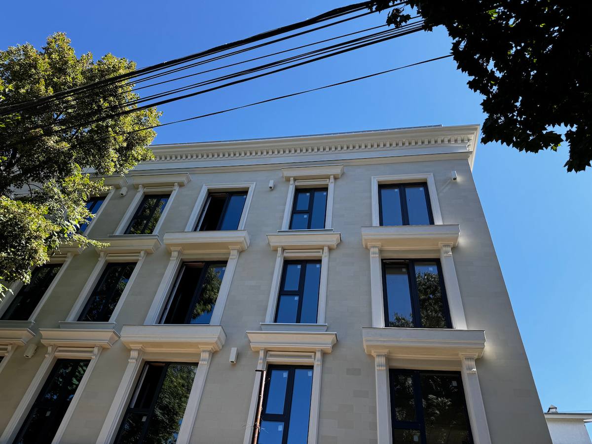 Classical-style building with pilasters, cornices and tall windows, clad in beige flexible stone