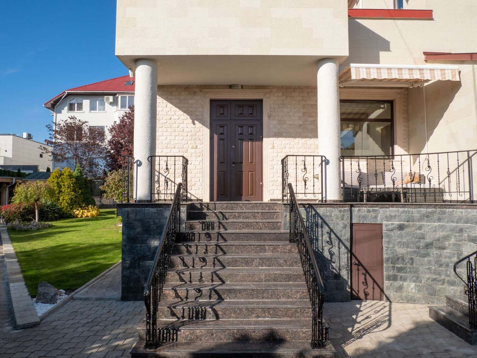 Main entrance with steps, wrought-iron railings and two round columns clad in flexible stone