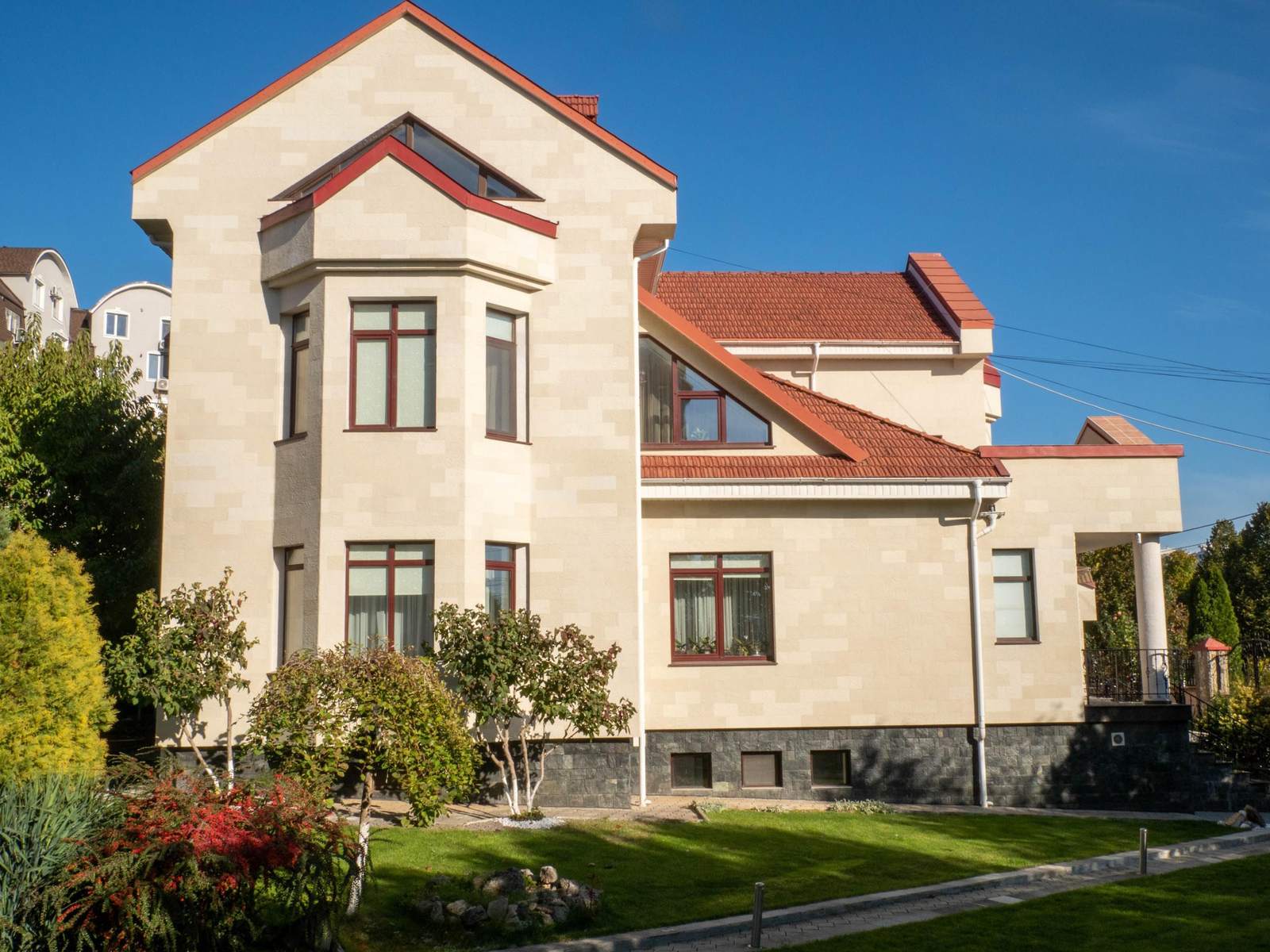 General view of the house from the lawn: bay window, gables and a red tiled roof