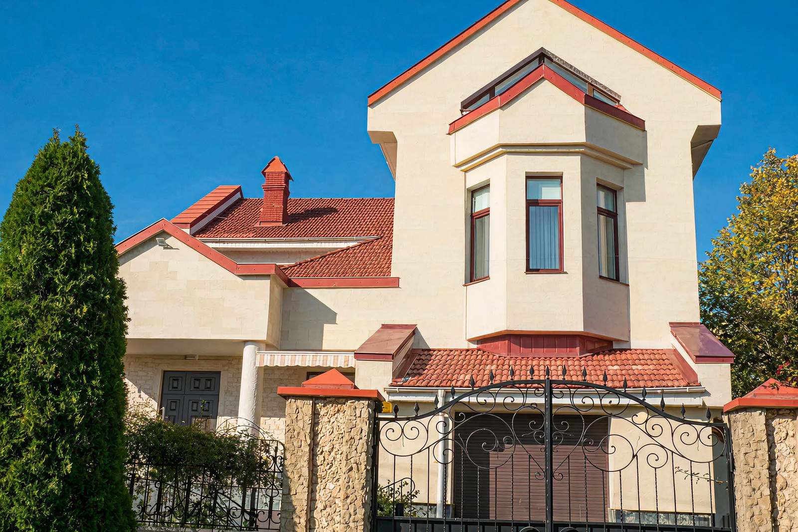 View from the gate: house with a red roof and a light flexible stone facade