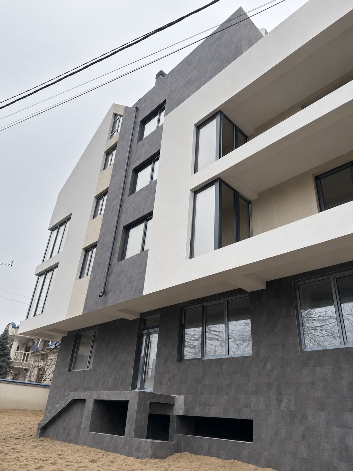 Facade with white volumes and Royal Granite cladding on the ground floor and the vertical band, seen from below