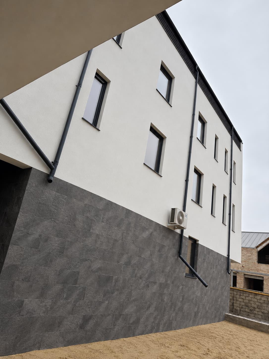 Side facade: tall Royal Granite plinth below the white wall with small windows