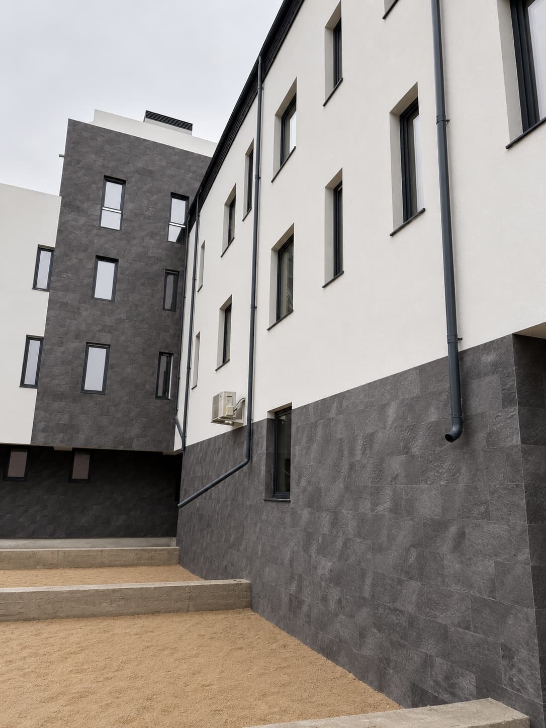Courtyard: a volume fully clad in Royal Granite next to the white wing on a flexible-stone plinth