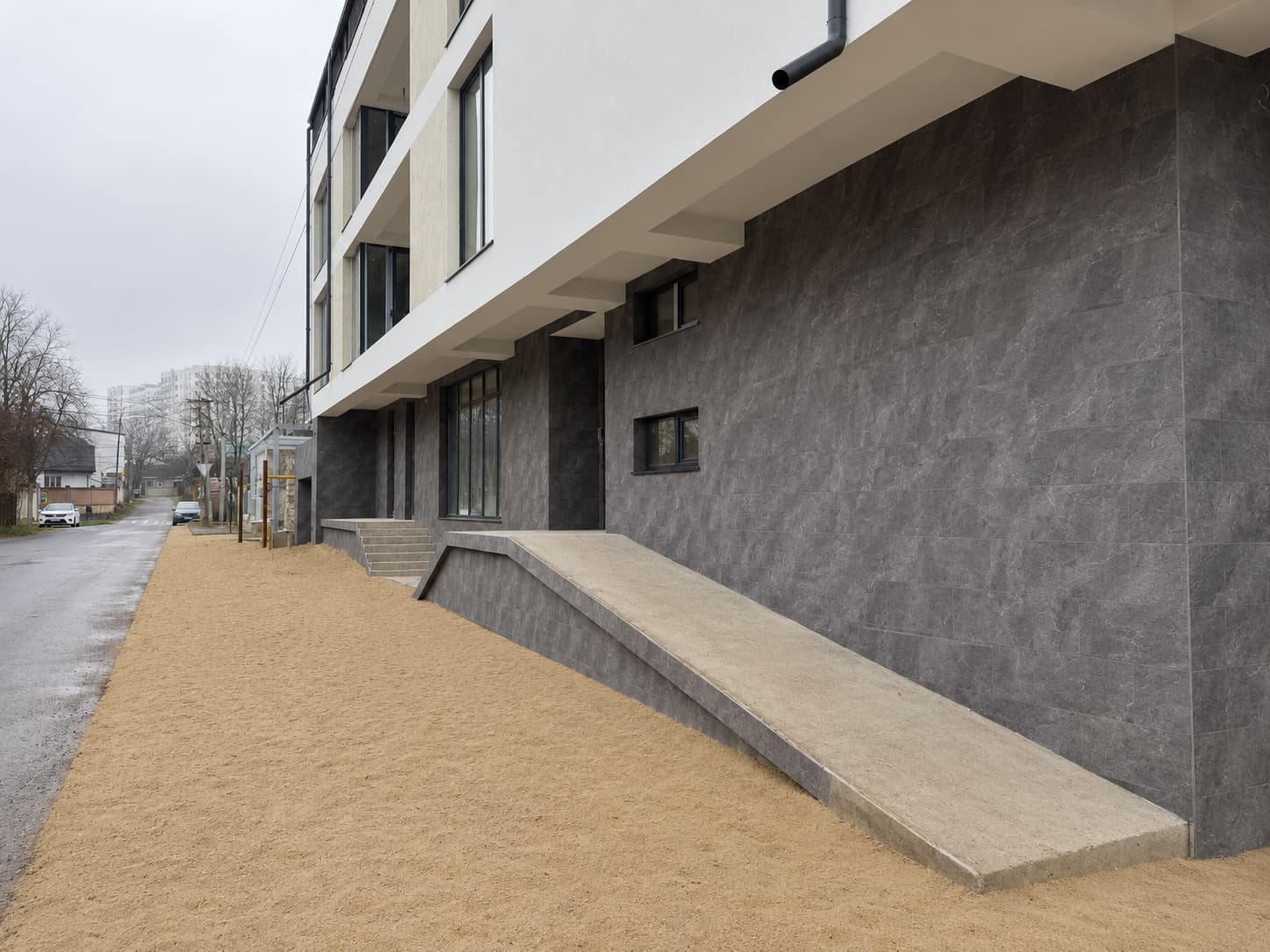 Street facade: Royal Granite ground floor with an access ramp below the white upper floors