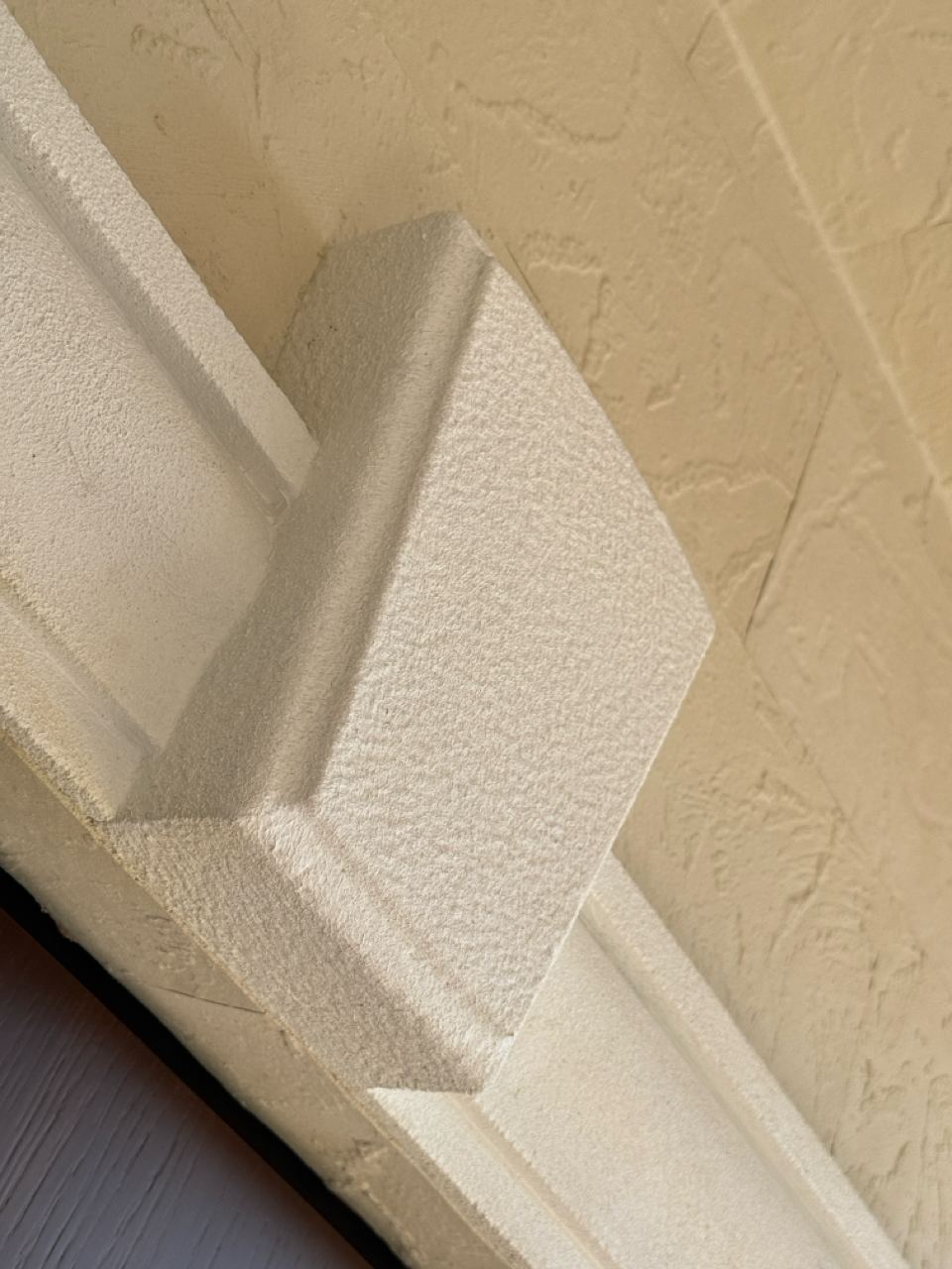 White capital on a corner clad in light flexible stone, photographed from below