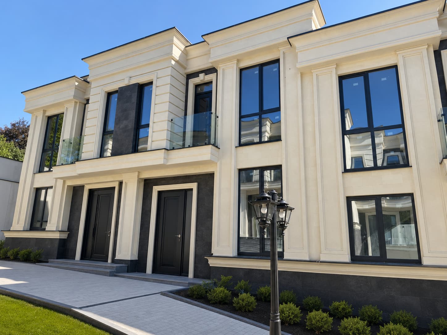 Front facade of the complex: beige registers with pilasters, anthracite plinth, entrance doors and lawn