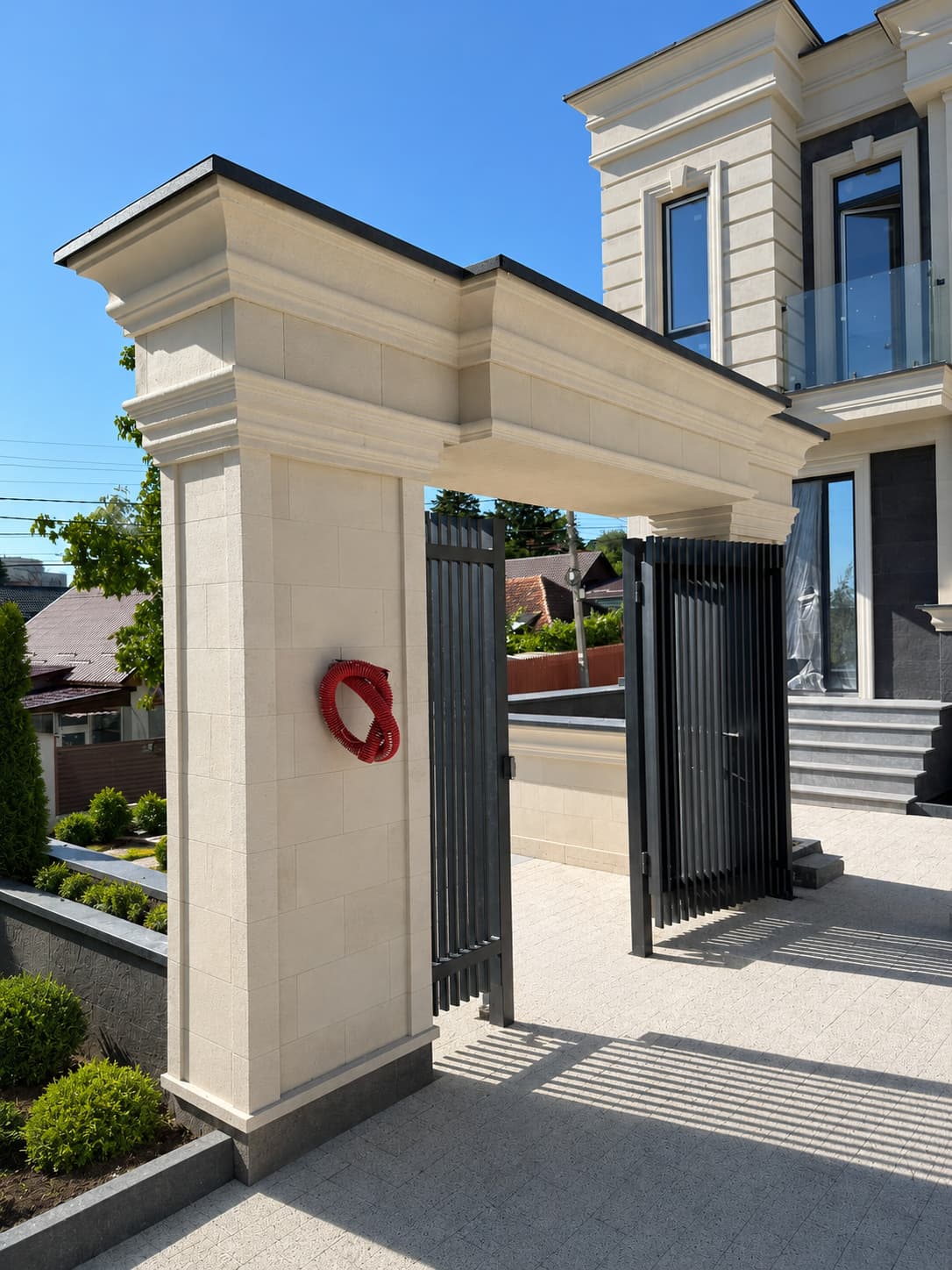 Entrance arcade clad in the same flexible stone as the facade, with a black metal gate
