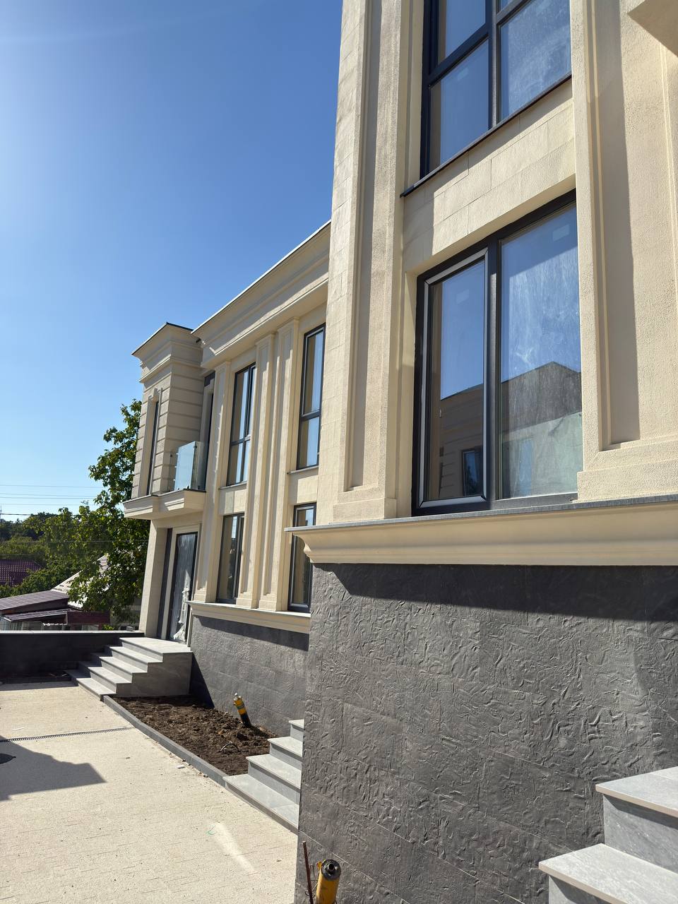 Corner of one house: beige field with pilasters, anthracite plinth and grey steps, shot from below