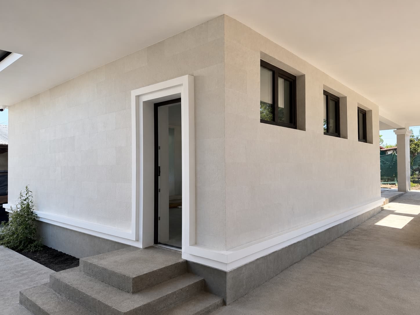 Side wing in light flexible stone, white door surround and grey plinth