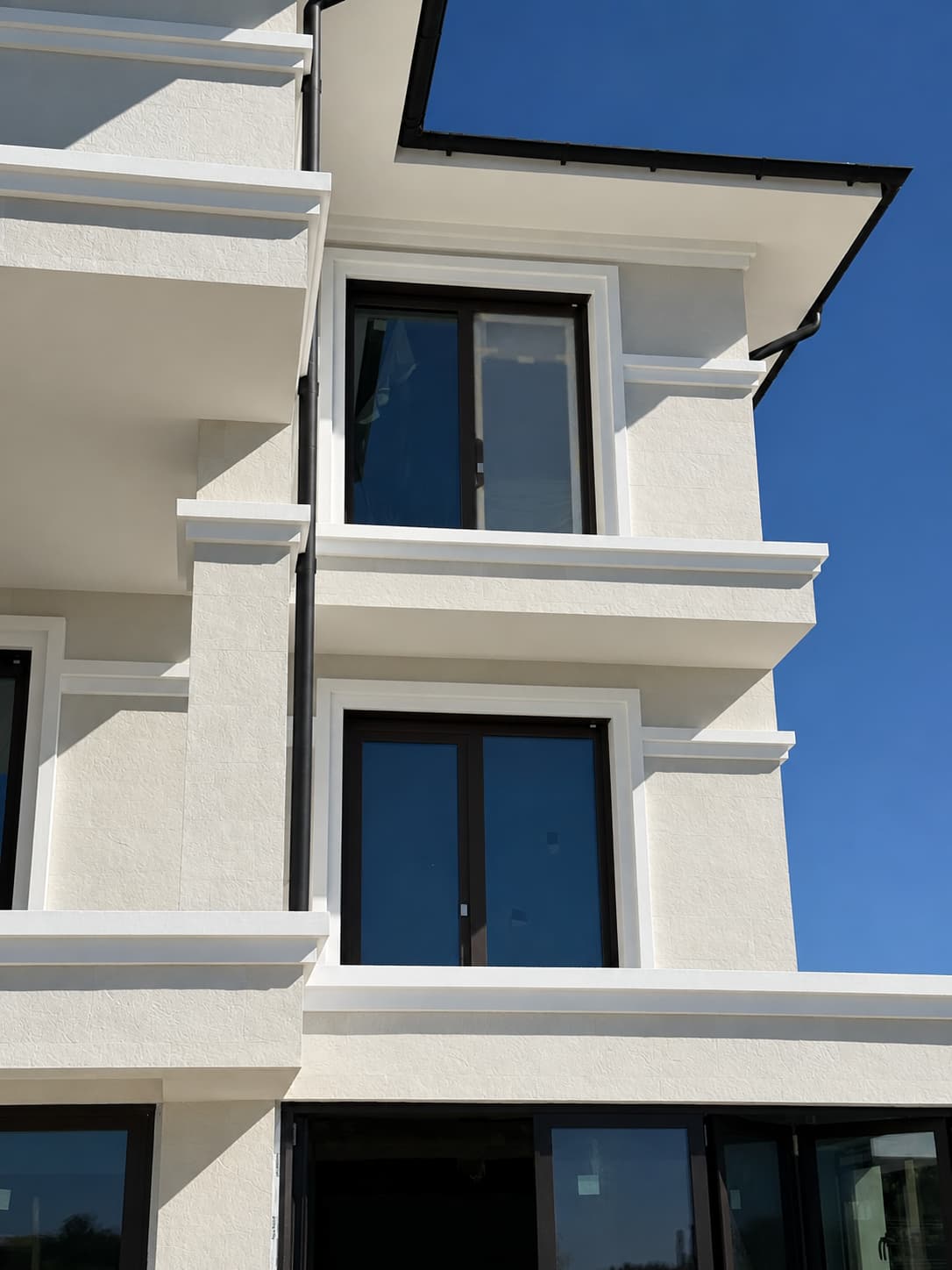Corner with balconies on three storeys, black windows and white cornices, photographed from below